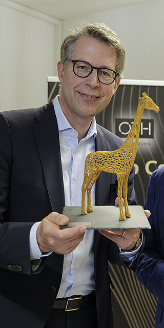 Prof. Dr. Sean Patrick Saßmannshausen (rechts) überreichte Markus Blume die Gründungsgiraffe „Raphi“, das Maskottchen des Start-up Centers, als Andenken. Foto: OTH Regensburg/Florian Hammerich
