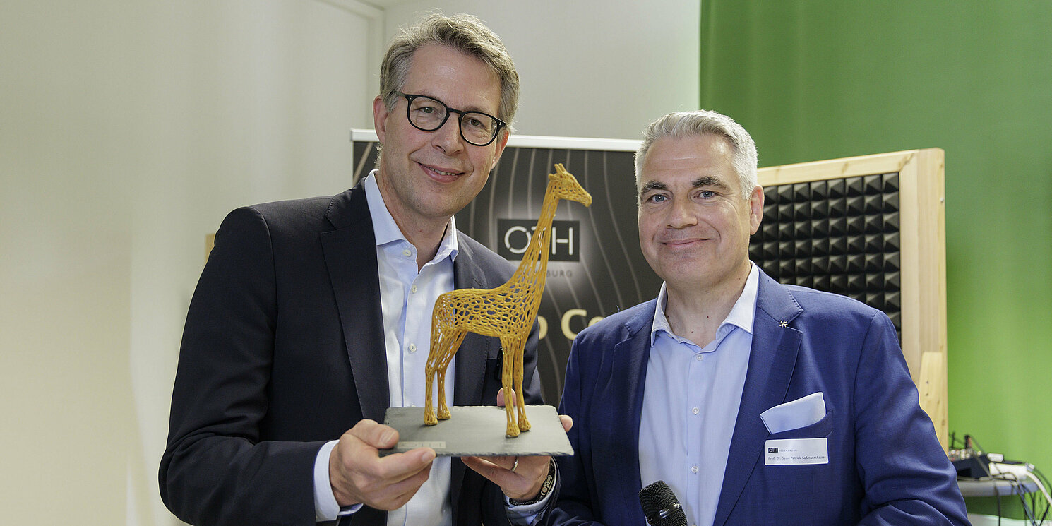 Prof. Dr. Sean Patrick Saßmannshausen (rechts) überreichte Markus Blume die Gründungsgiraffe „Raphi“, das Maskottchen des Start-up Centers, als Andenken. Foto: OTH Regensburg/Florian Hammerich