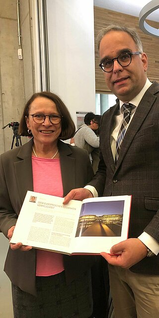 Oberbürgermeisterin Gertrud Malz-Schwarzfischer überreicht Wolfgang Voigt den druckfrischen Almanach. Foto: Roman Danzer Eine Frau und ein Mann stehen nebeneinander und lächeln in die Kamera. Der Mann hält ein aufgeschlagenes Buch in die Kamera.