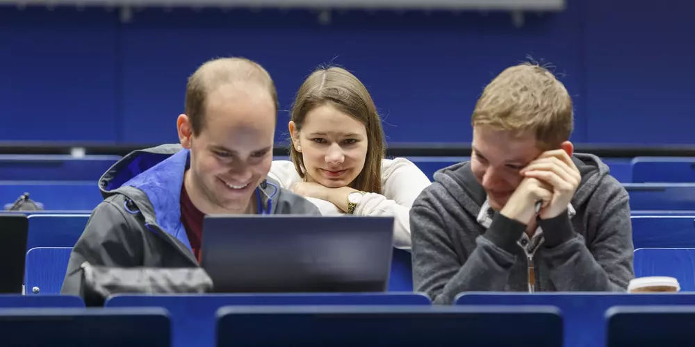 Three young people looking into a laptop