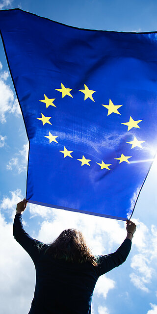 Eine Frau hält die EU-Fahne.