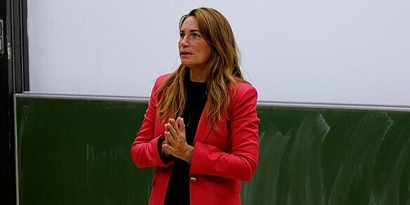 Prof Dr Ina Schildbach from the Faculty of Social and Health Sciences focuses on the topic of poverty. Photo: Herbert Baumgärtner A woman in a red blazer stands in a lecture hall.