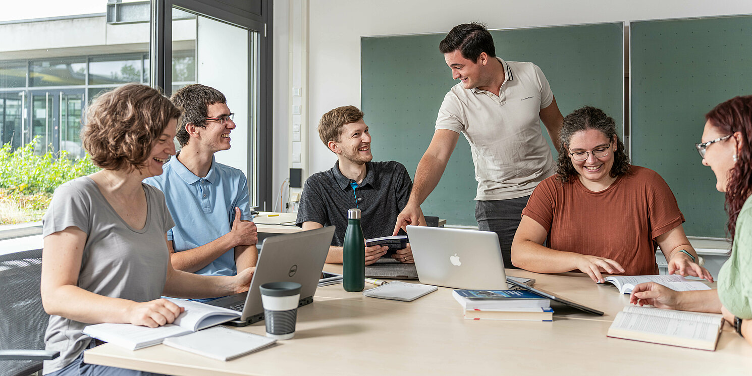 Interne Fortbildungsangebote für Mitarbeiterinnen und Mitarbeiter der OTH Regensburg Studierende arbeiten in einer Lerngruppe mit Laptops und Unterlagen an einem großen Tisch.