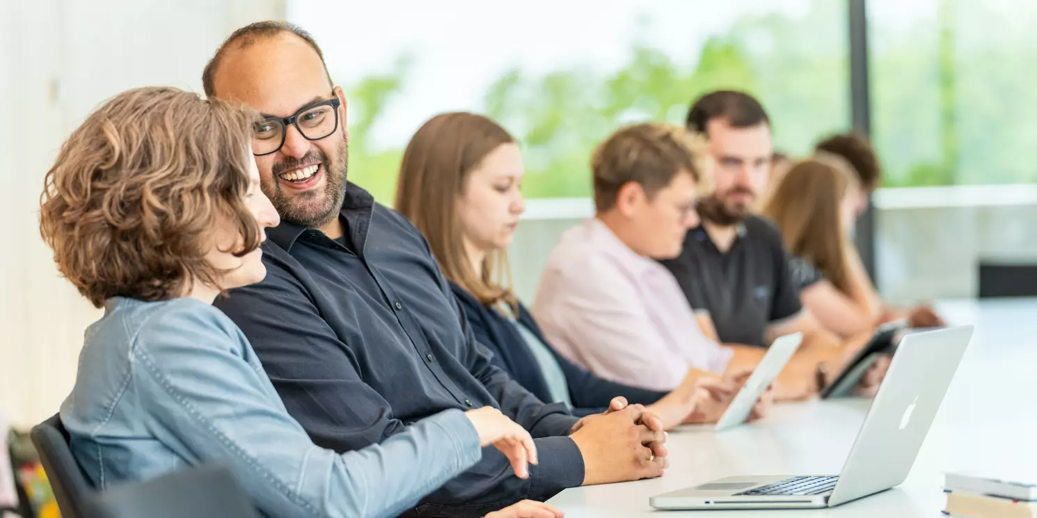 Studierende lernen und unterhalten sich in einem Seminarraum. 