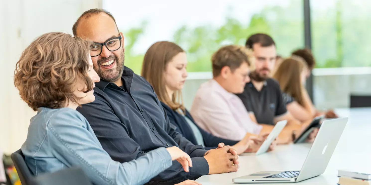 Studierende lernen und unterhalten sich in einem Seminarraum. 