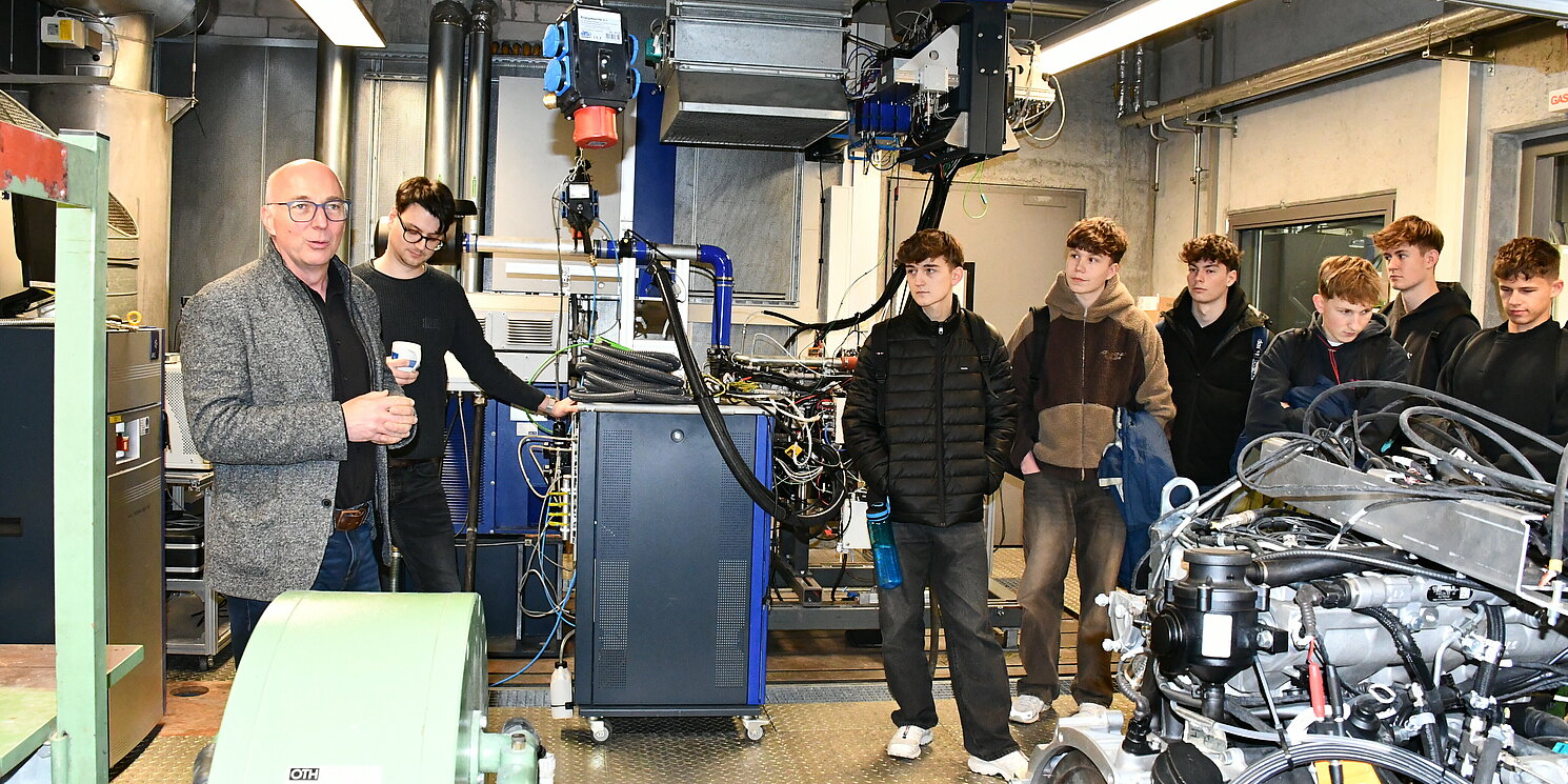 Ein Mann spricht zu einer Gruppe junger Menschen in einem Labor.