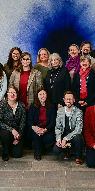 Gruppenfoto vor einer Wand mit blauem Kunstwerk