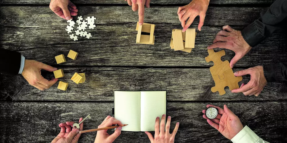 Several hands working on different things at the same table