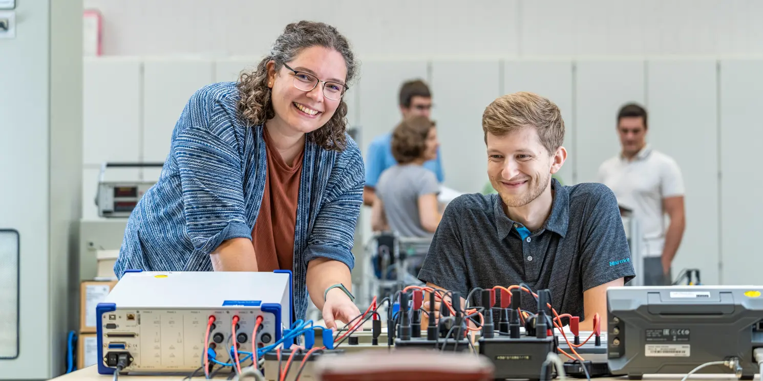 Study Car IT and Electronics part-time Zwei Studierende arbeiten in einem Labor an einem elektronischen Schaltkasten.